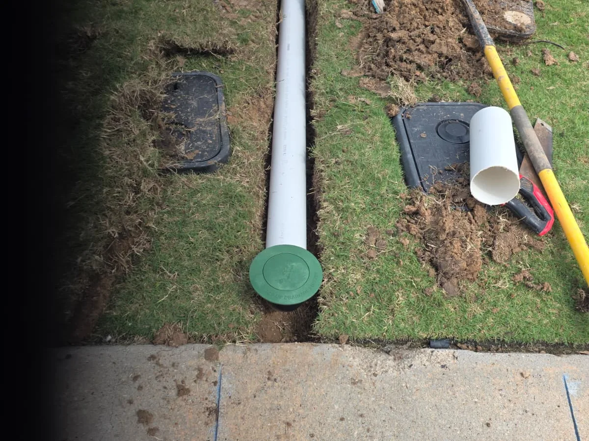 Drain line and catch basin being installed in a lawn