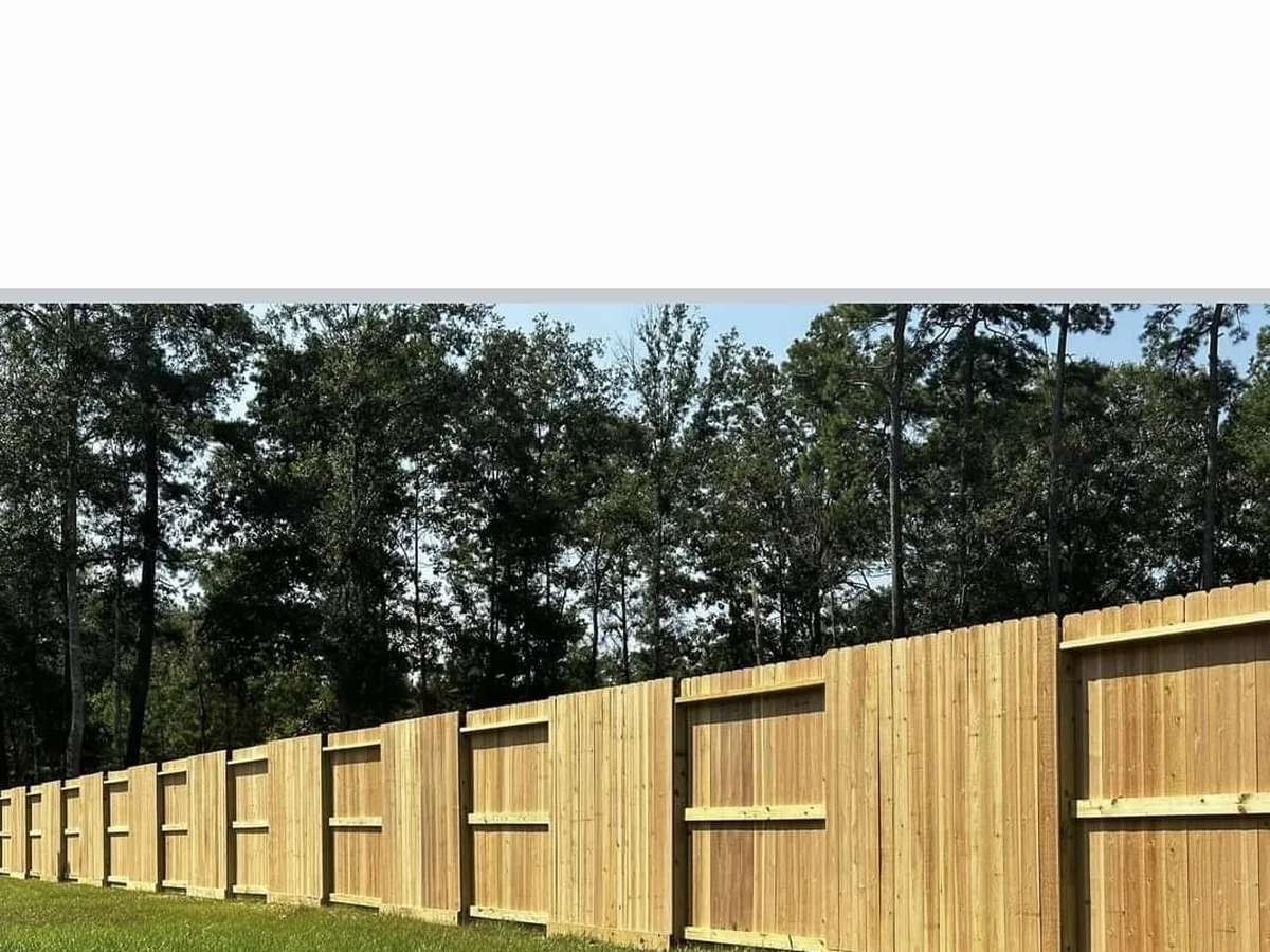 Cedar fence panels with framed sections under tall pines