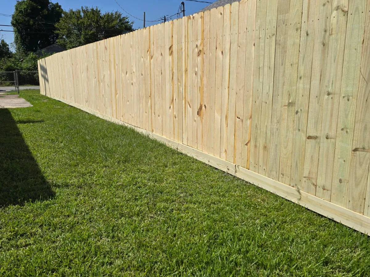 Long run of new pine fence against a blue sky