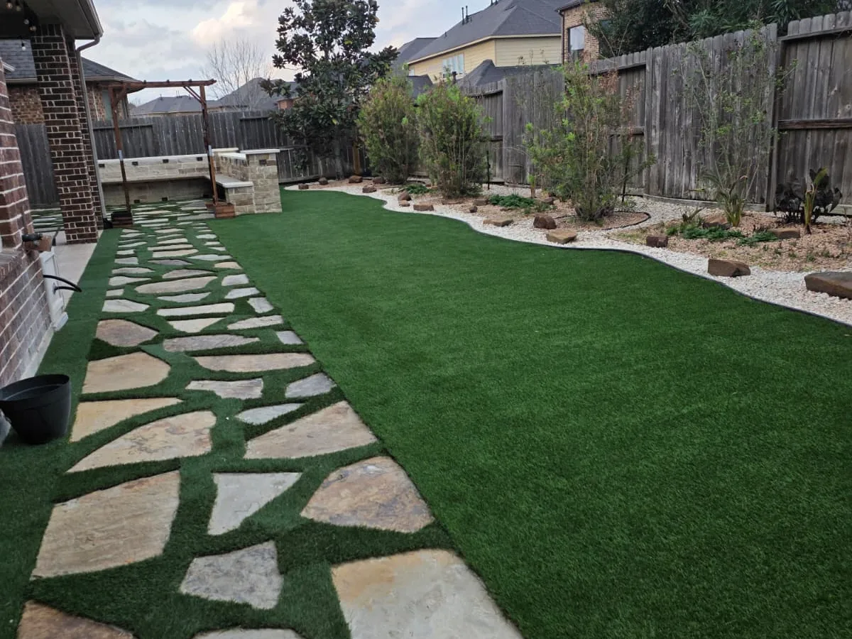 Long artificial-turf side yard with flagstone path and gravel beds
