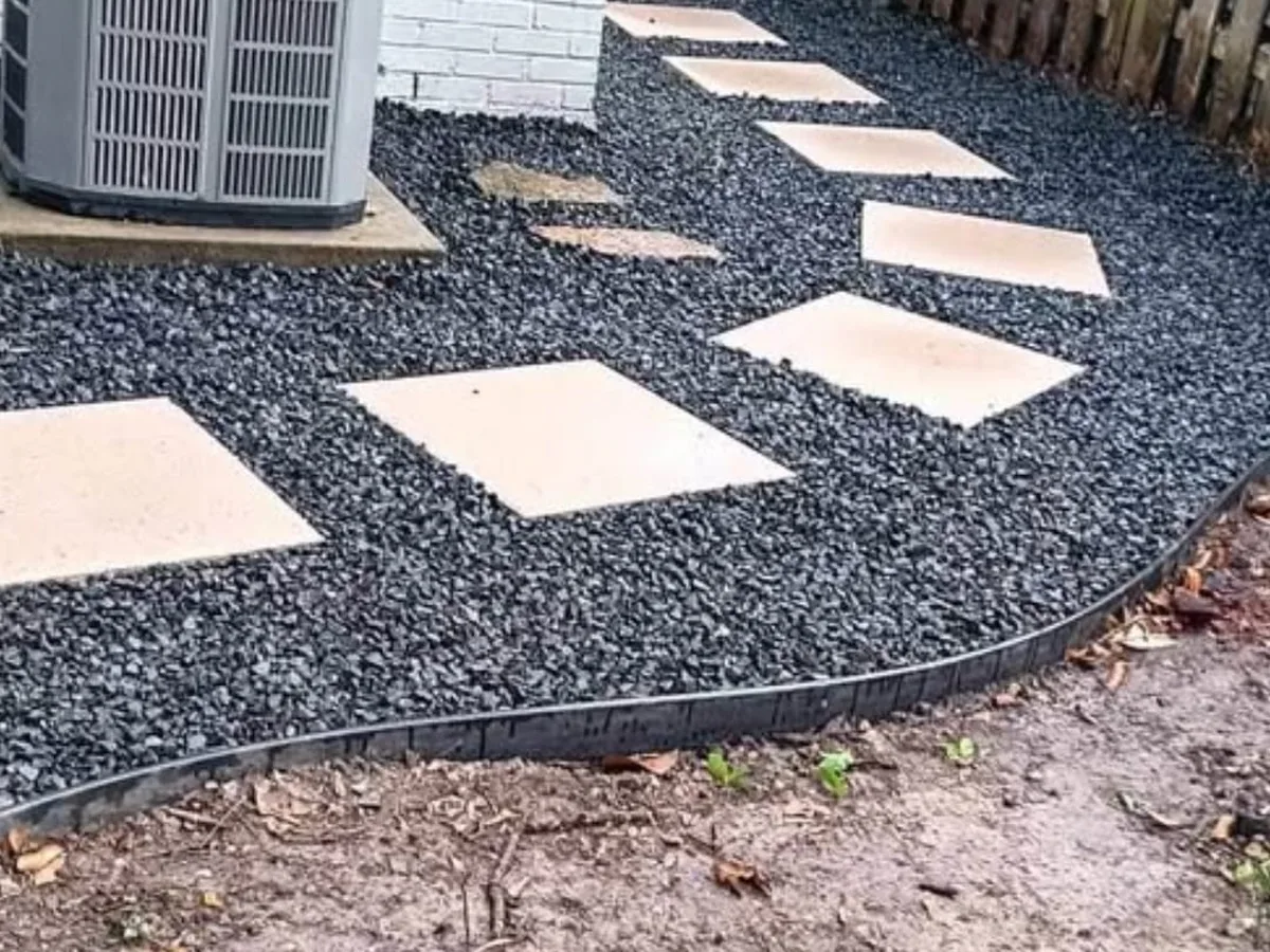 Stepping pads in black gravel around an AC unit