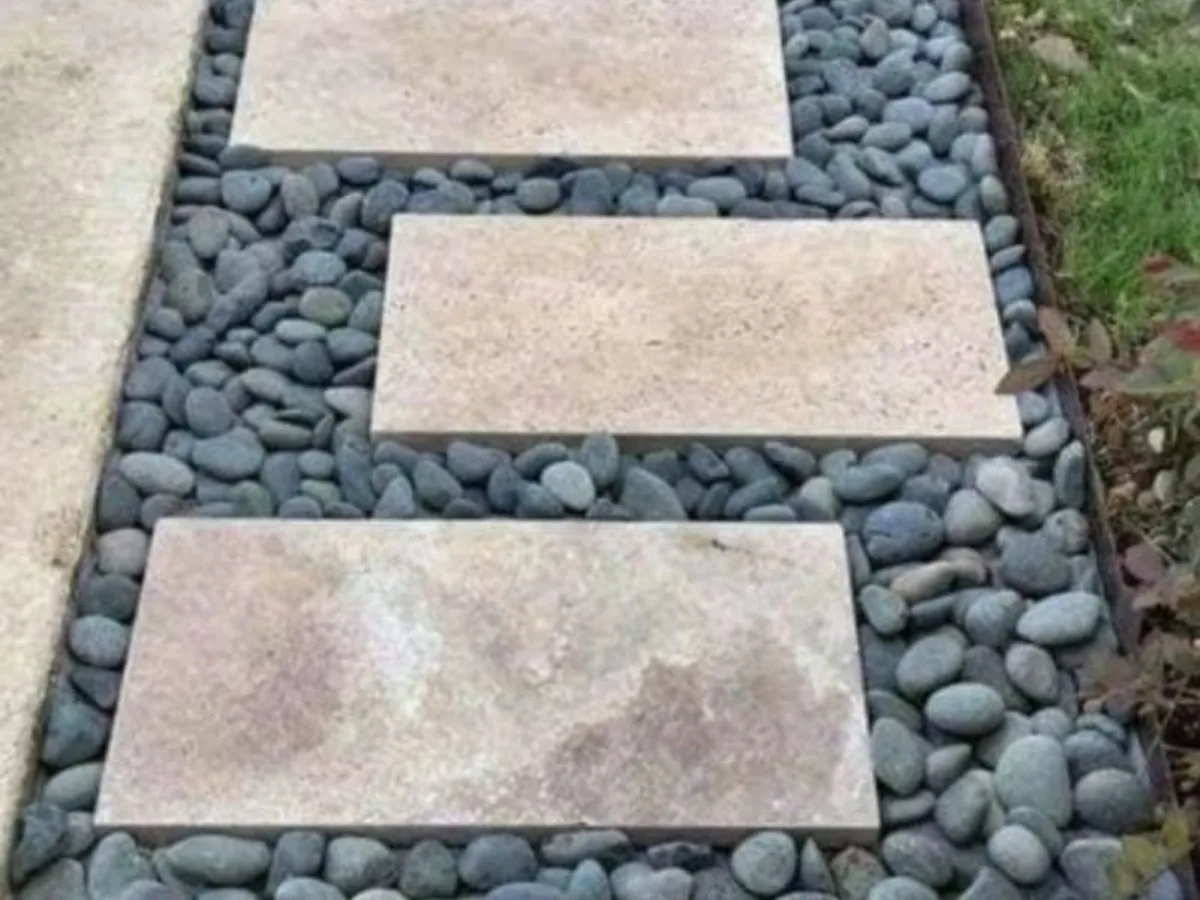 Stepping stones set in river rock beside a lawn