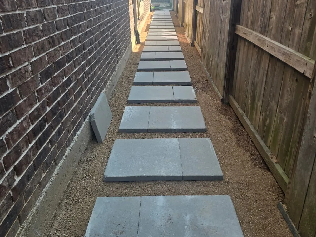 Stepping-pad path along a brick house with gravel drainage